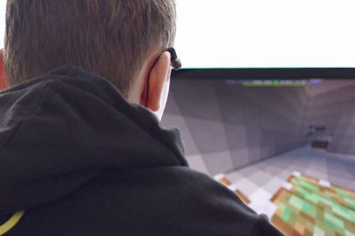 Gracz przed monitorem komputerowym podczas rozgrywki w Minecraft
